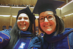 Selfie of Corryn and Mary on stage at the Doctoral Hooding Ceremony.